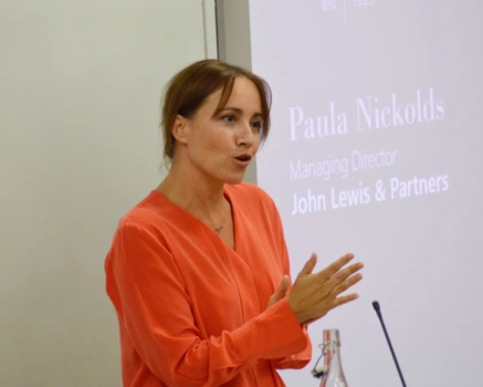 Paula Nickolds, speaking at a podium or presentation, who provided this testimonial about Sam's coaching and leadership.